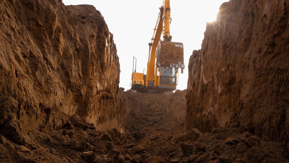 Excavator Digging a Trench Between Steep Dirt Walls — A & S Cuthel Earthmoving & Transport in Bellingen, NSW