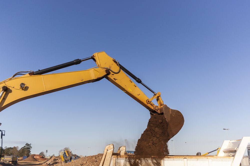 Yellow Excavator Dumping Dirt — A & S Cuthel Earthmoving & Transport in Armidale, NSW