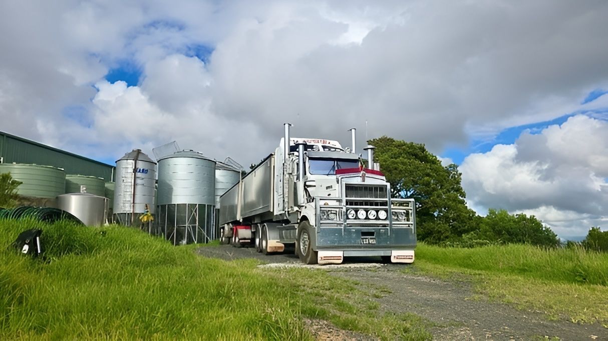 Semi Truck Beside Silver Grain Silos on A Grassy Farm Road — A & S Cuthel Earthmoving & Transport in Nambucca Heads, NSW