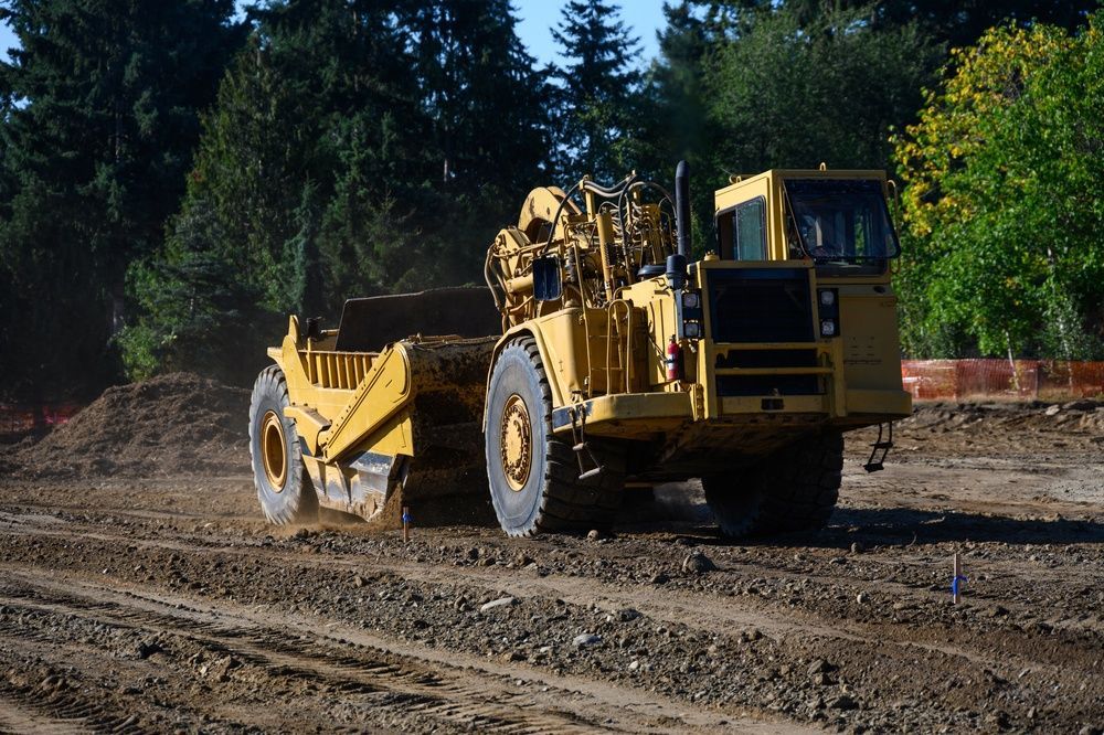 Yellow Road Grader Leveling a Dirt Road — A & S Cuthel Earthmoving & Transport in Coffs Harbour, NSW