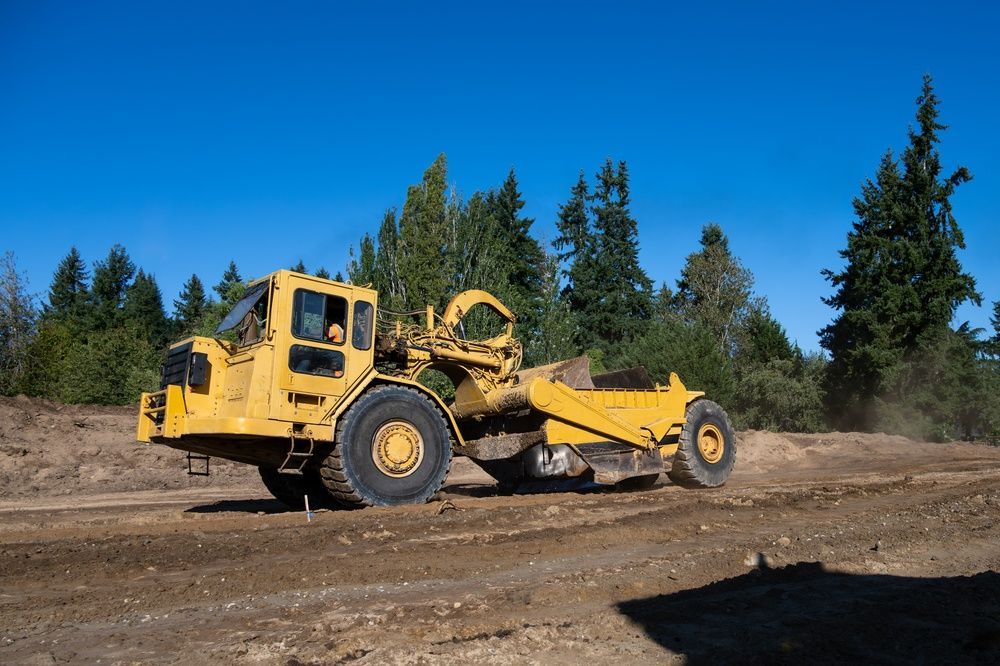 Yellow Road Grader on a Dirt Road — A & S Cuthel Earthmoving & Transport in Dorrigo, NSW
