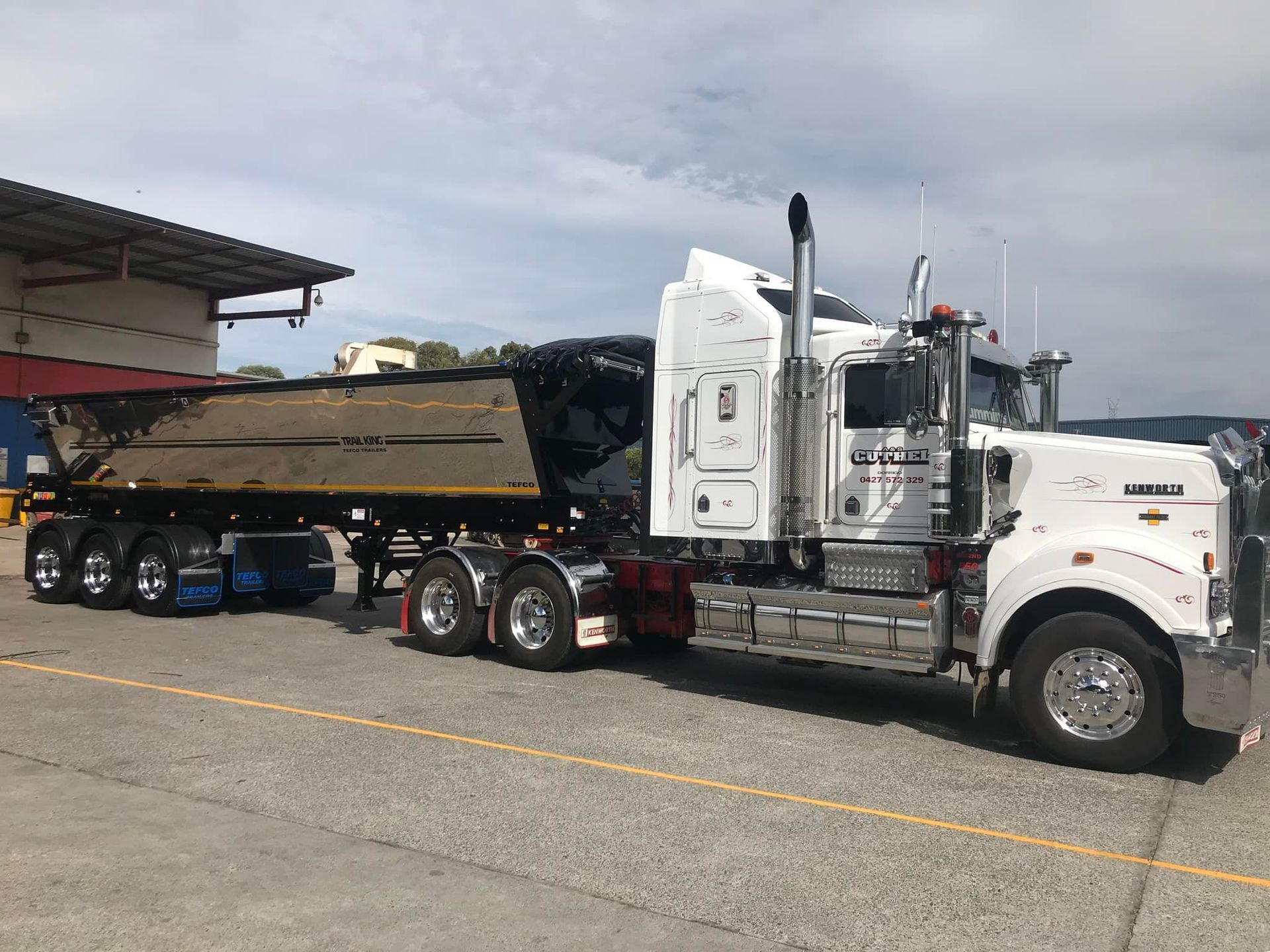 White Semi Truck Hauling a Black And Gold Dump Trailer in A Parking Lot — A & S Cuthel Earthmoving & Transport in Grafton, NSW