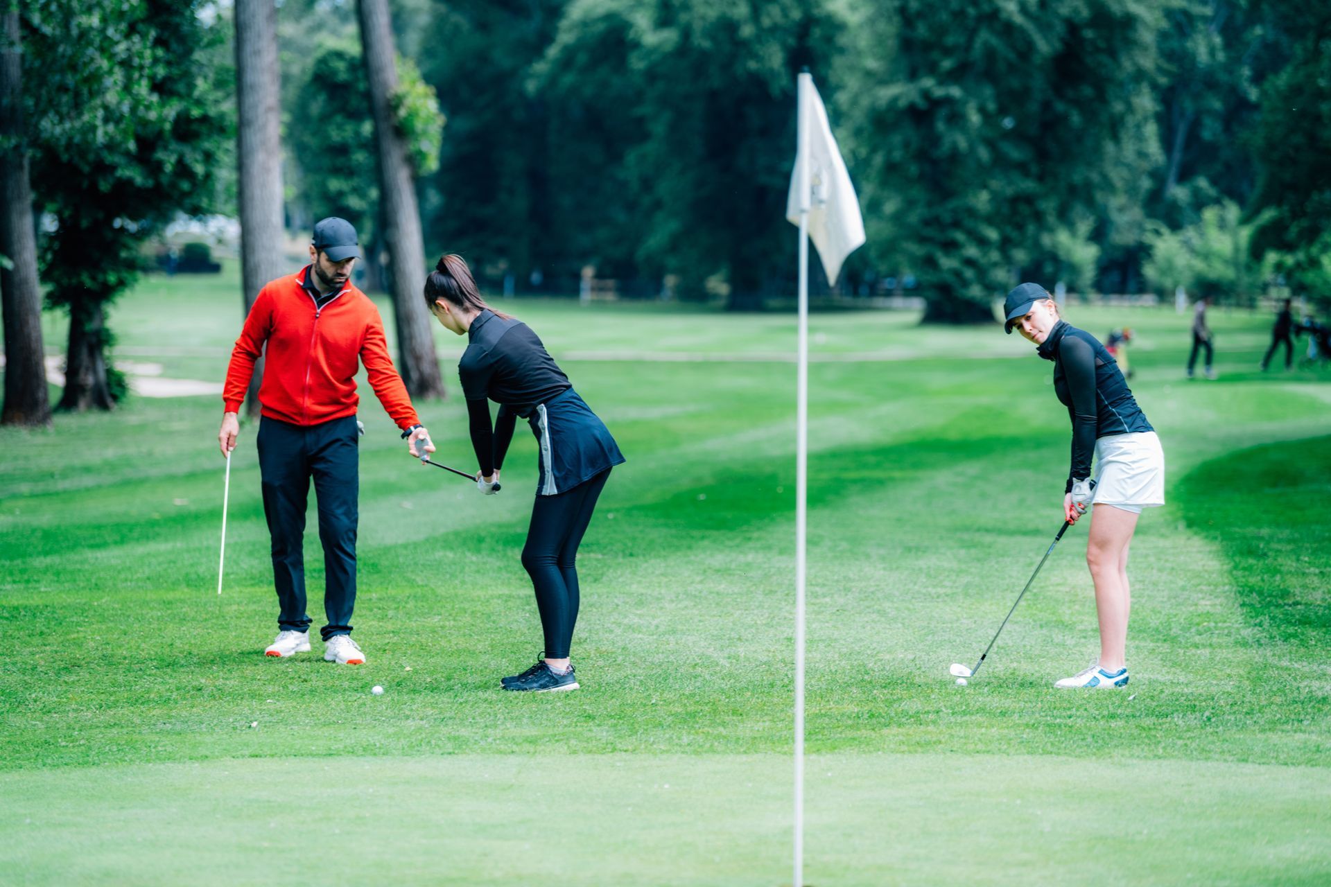 A man and two women are playing golf on a golf course.