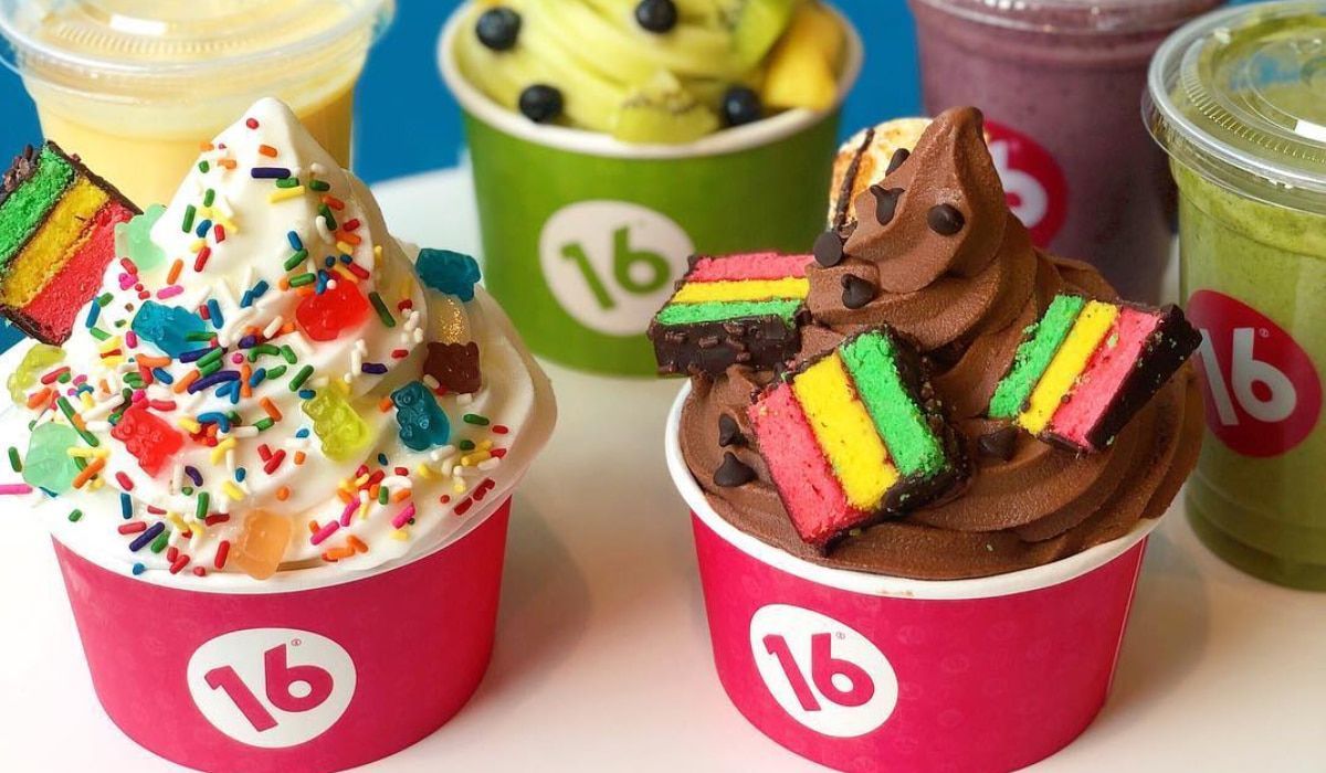Several cups of frozen yogurt and smoothies, featuring colorful toppings and a branded 