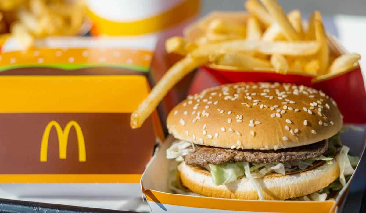 A McDonald's meal on a tray, including a burger in a box, a carton of french fries, and a drink cup.