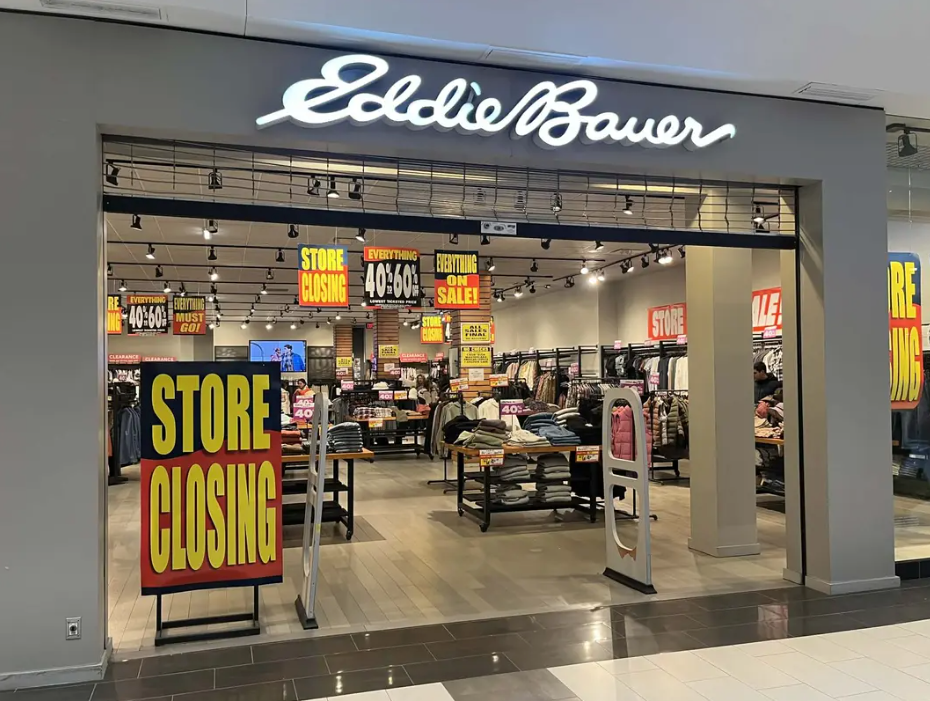 Storefront of an Eddie Bauer shop inside a mall with multiple signs announcing a store closing sale.