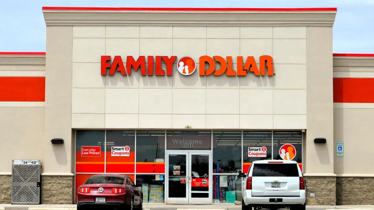A Family Dollar store storefront with red lettering and accents, featuring a red car and a white SUV parked in front.
