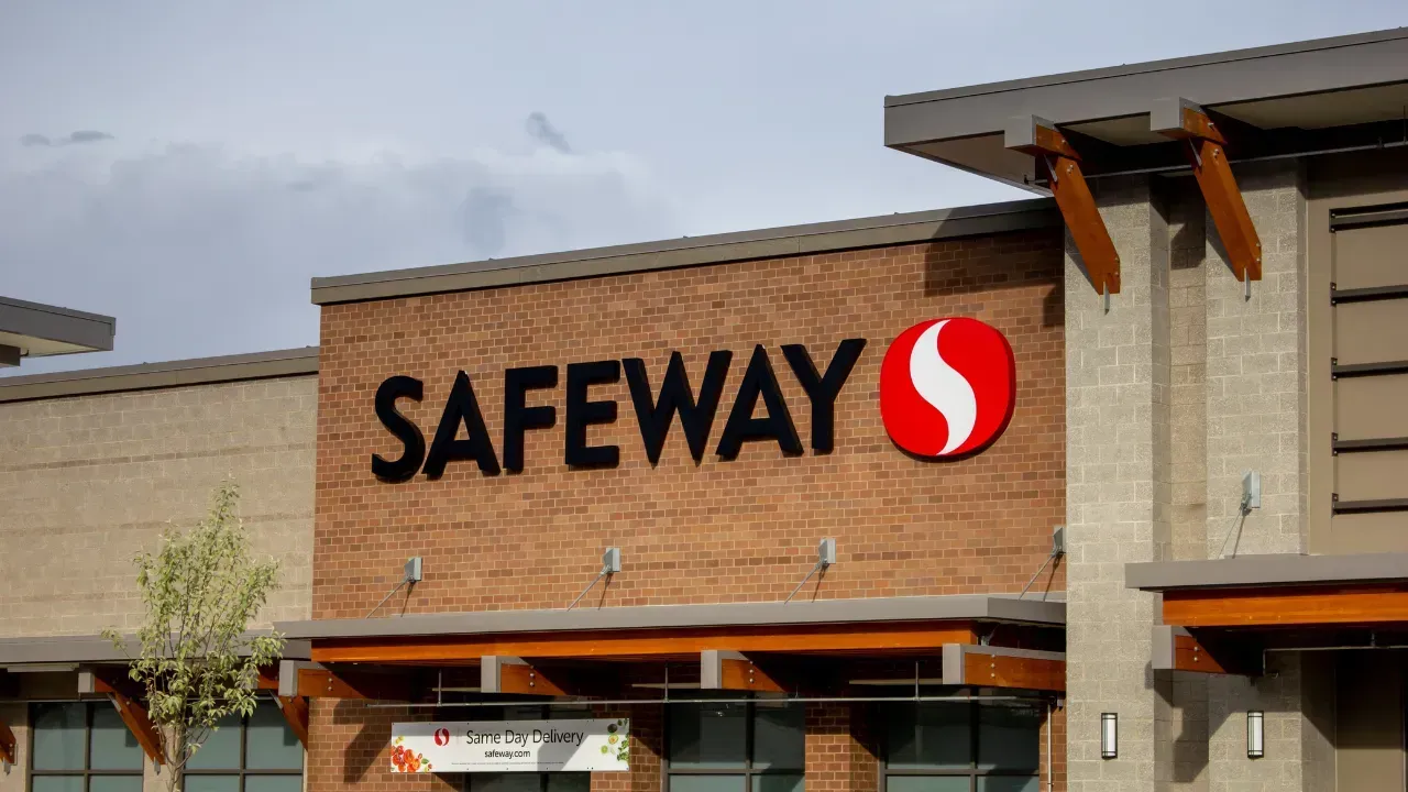 Exterior view of a Safeway grocery store with the company logo and name in red and black on a brick facade.