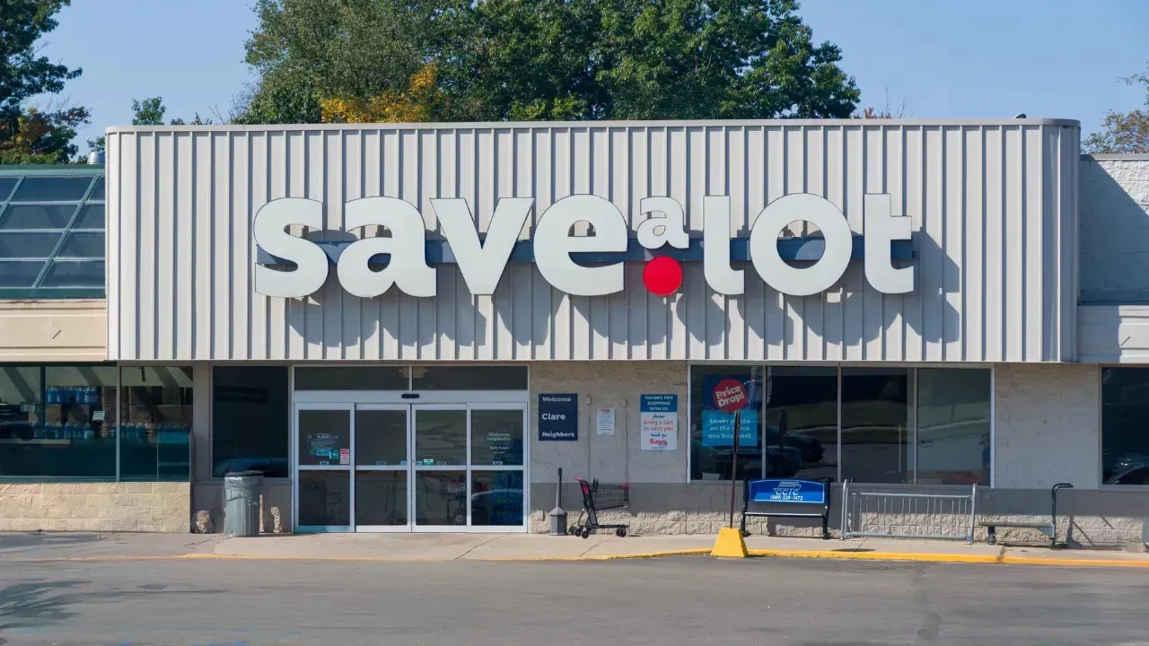 A Save A Lot grocery store storefront with a gray corrugated metal facade and sliding glass entry doors.