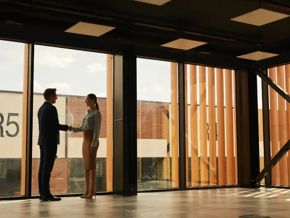 The main entrance of the NuHAA building, featuring a modern glass and stone facade, at sunset.