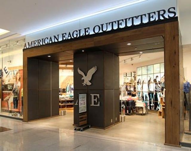 Storefront of an American Eagle Outfitters with dark wood paneling, an eagle logo, and interior clothing displays.
