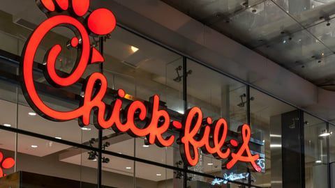 A large, red, 3D Chick-fil-A logo mounted on a glass building exterior.