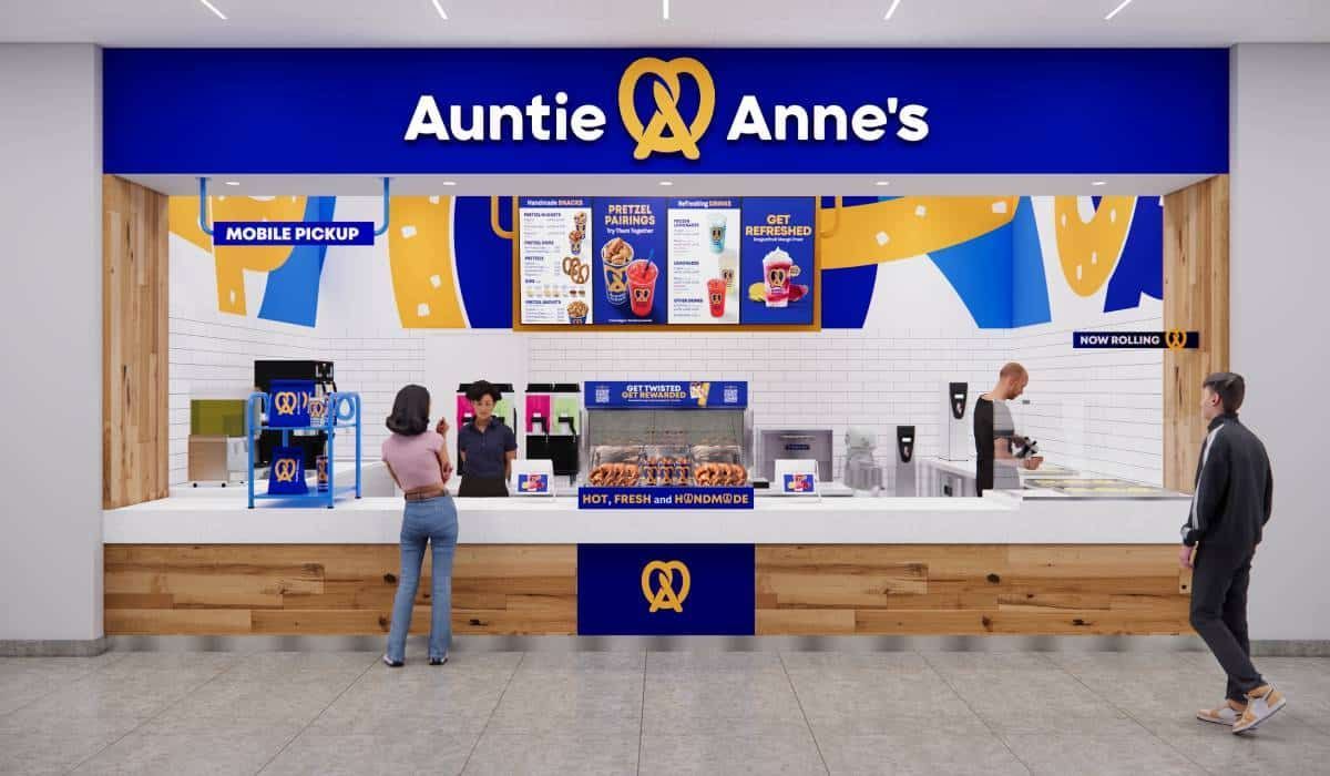 A bright, modern Auntie Anne’s pretzel shop interior with a blue and white color scheme and customers at the service counter.