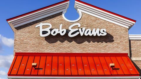 The exterior signage and red metal roof of a Bob Evans restaurant against a clear blue sky.