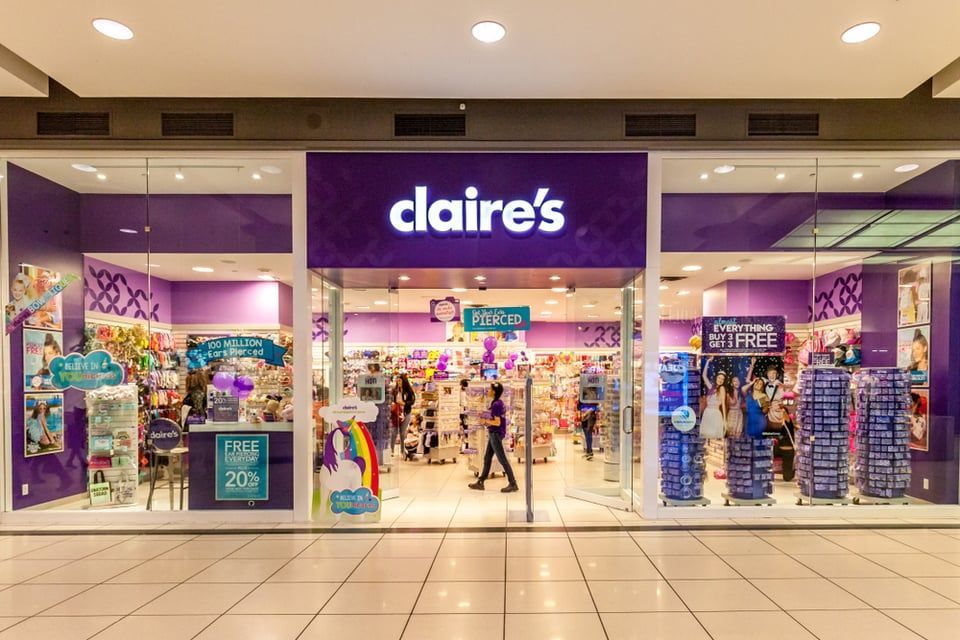 A Claire's retail store at a shopping mall with bright purple branding, product displays, and a glass-front entrance.