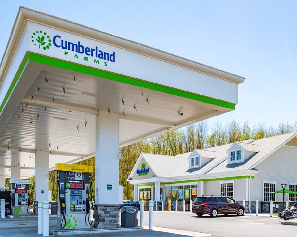 A Cumberland Farms gas station with a white canopy and store building under a clear blue sky.