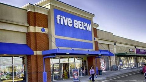 A Five Below store storefront with a blue sign, blue awnings, and brick accents in a strip mall shopping center.