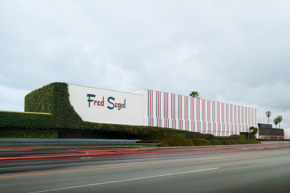 A Fred Segal store building with green ivy walls and a striped white, red, and grey facade under a cloudy sky.