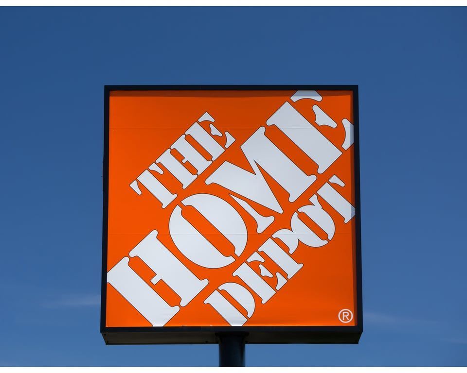 The orange and white square sign for The Home Depot against a clear blue sky.