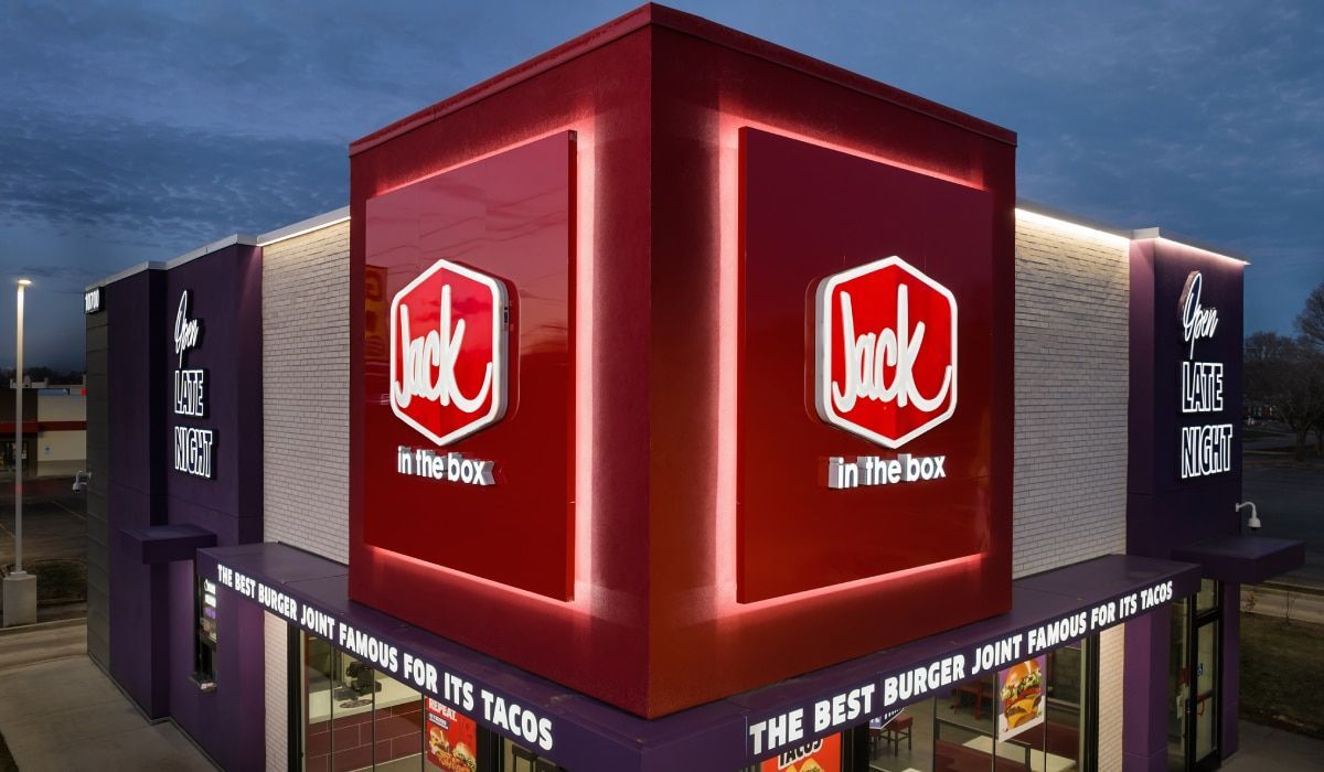 A modern, purple and red Jack in the Box restaurant exterior at twilight, featuring illuminated brand signage.