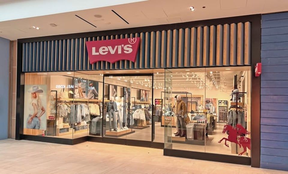 A Levi’s retail storefront with a red logo sign, glass windows displaying clothing racks, and red horse silhouettes.
