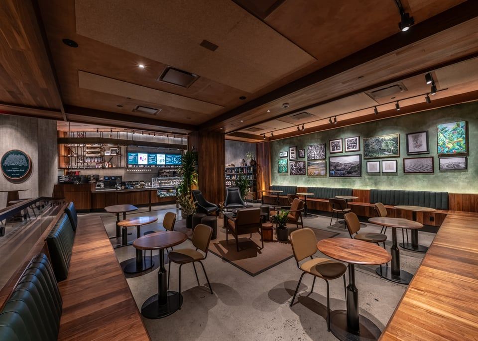 An upscale, dimly lit coffee shop interior with wooden paneling, a service counter, and varied seating arrangements.