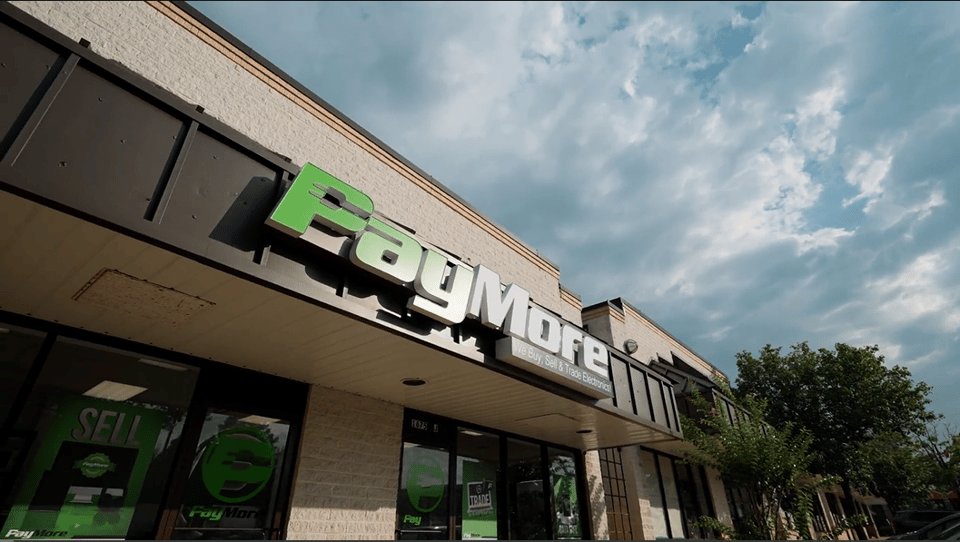 A PayMore storefront with a green sign under a cloudy sky.
