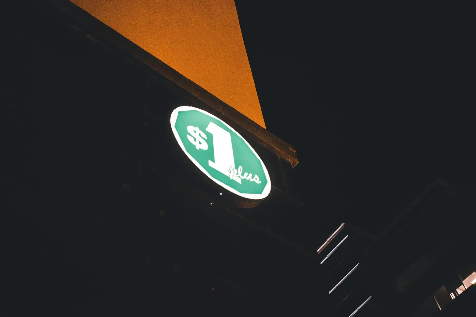 A green Publix Food & Pharmacy sign mounted on a white and beige building exterior against a blue sky.