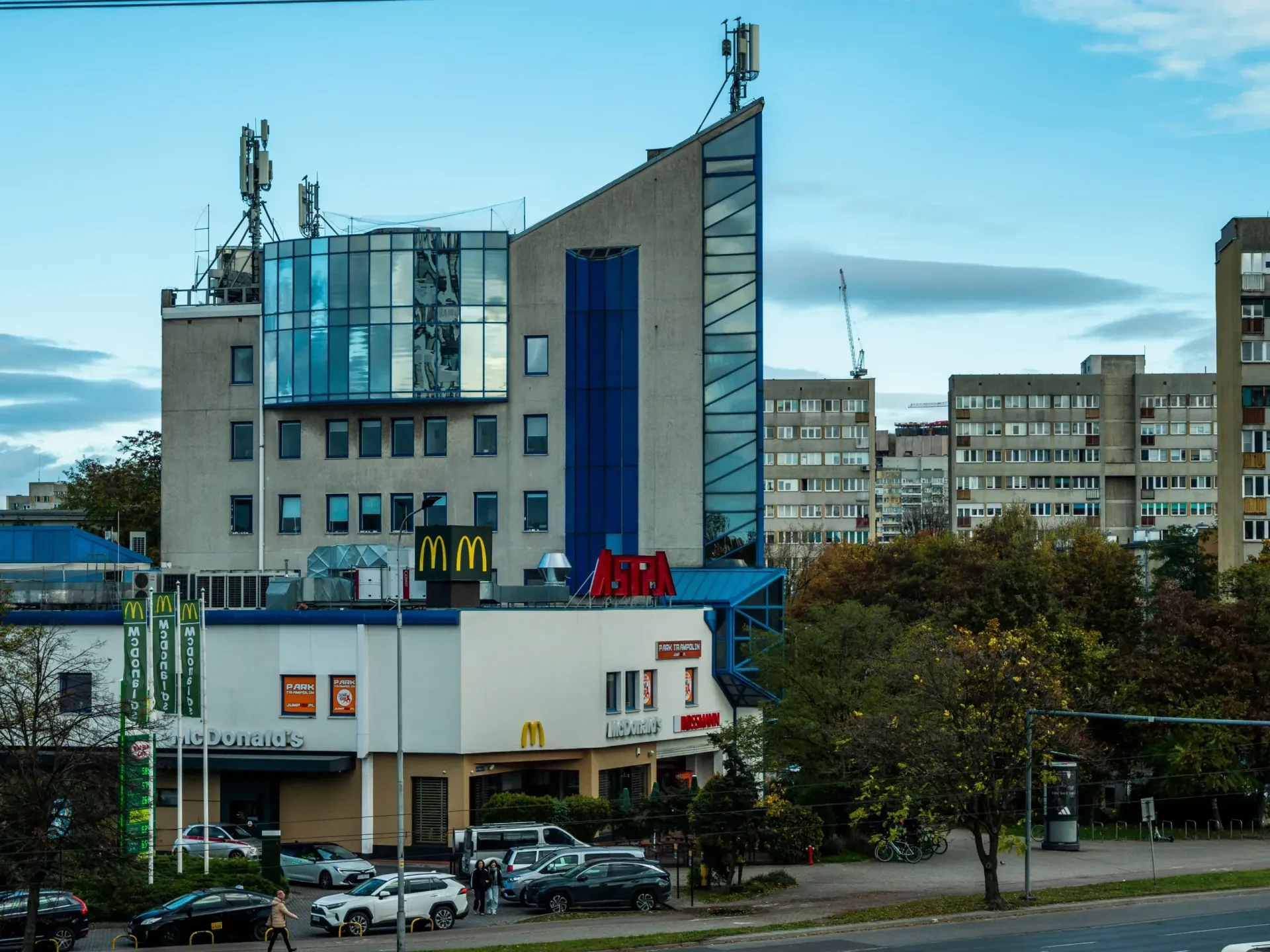 A McDonald's restaurant at the base of a modern, multi-story building with a distinctive pointed, blue-accented roof.