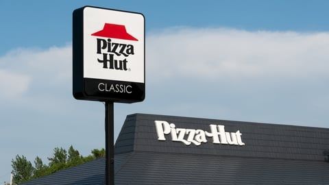 A Pizza Hut Classic restaurant sign stands outdoors against a blue sky, with a Pizza Hut logo on the building roof.