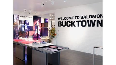 The interior of a Salomon store in Bucktown featuring a display table with footwear and branded wall signage.