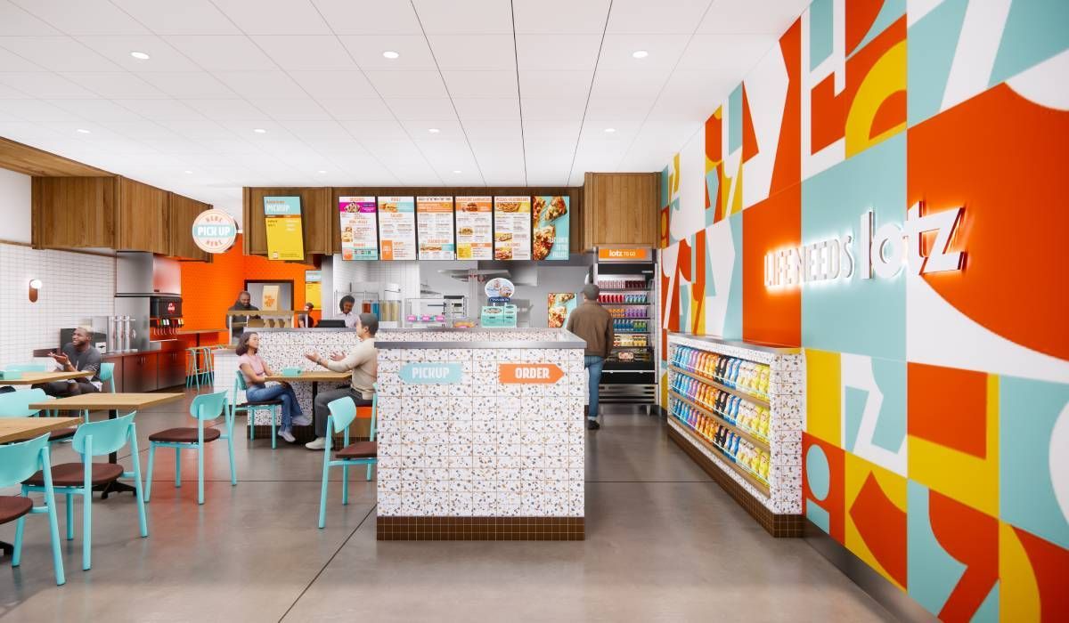 Modern cafe interior with teal chairs, a terrazzo service counter, and a vibrant, patterned wall featuring the name Crumbl.
