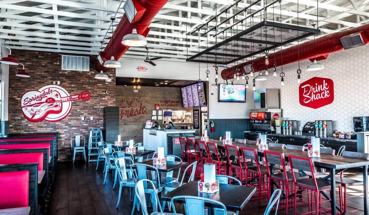 Interior of a casual restaurant featuring blue chairs, red accents, brick walls, and a