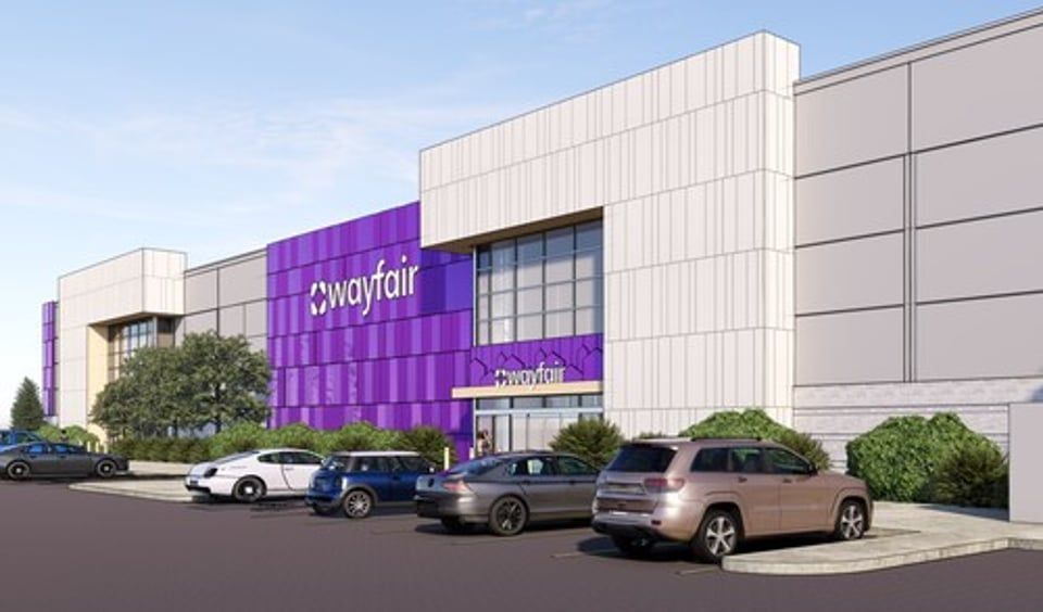 Exterior view of a modern Wayfair building with purple accents and a parking lot with several cars.