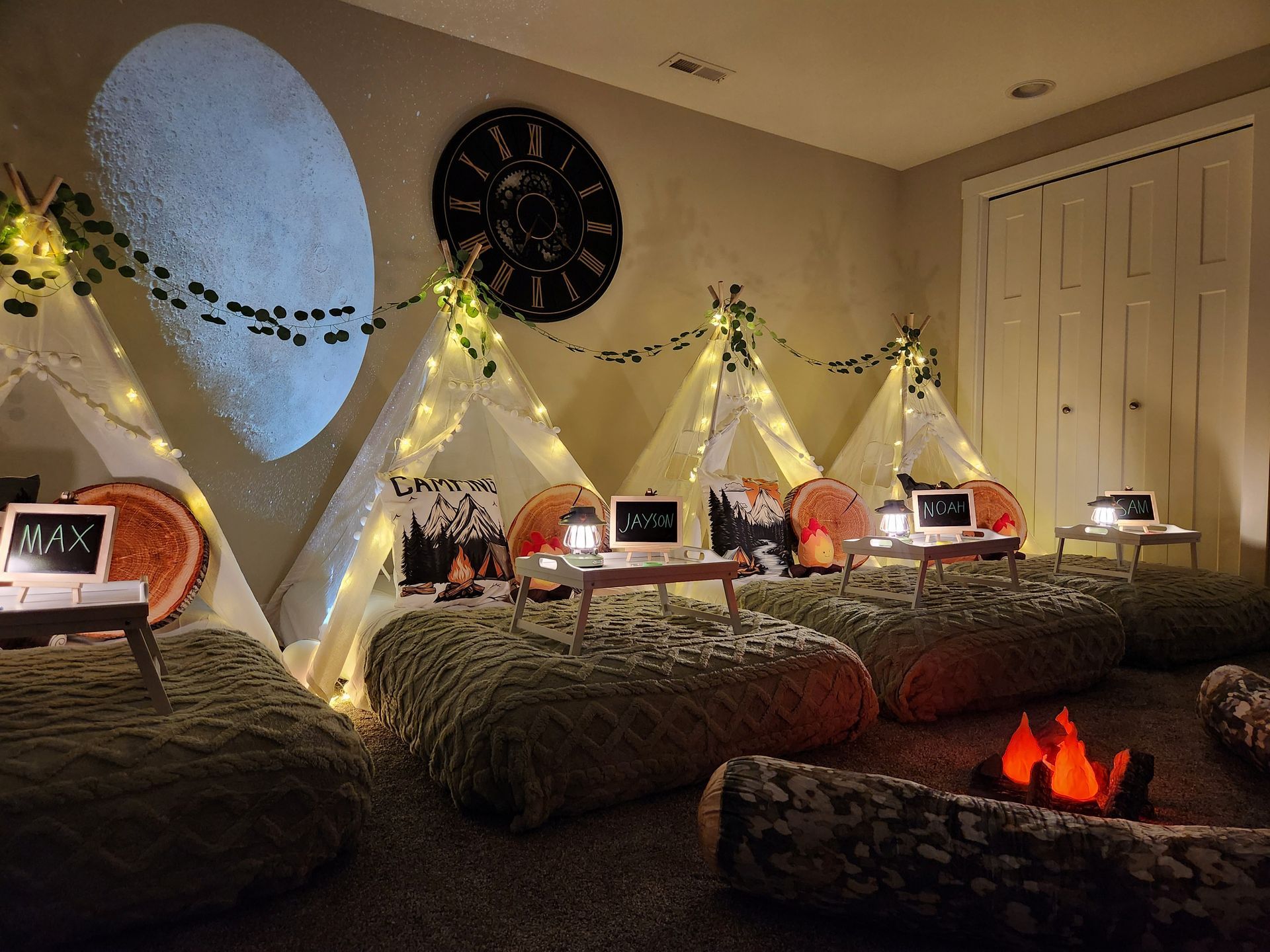 Camping themed indoor sleepover party with faux campfire and starry night projector