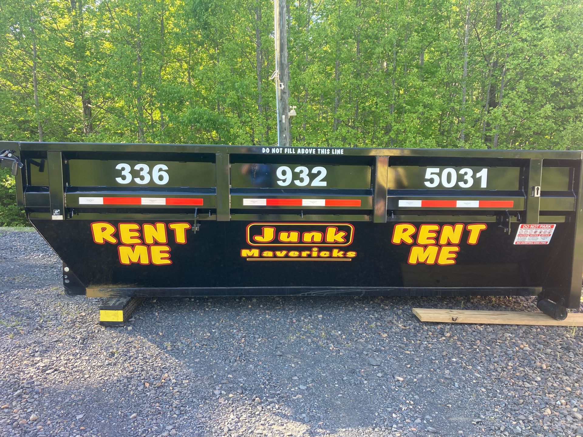 A dumpster filled with furniture is parked on the side of the road.