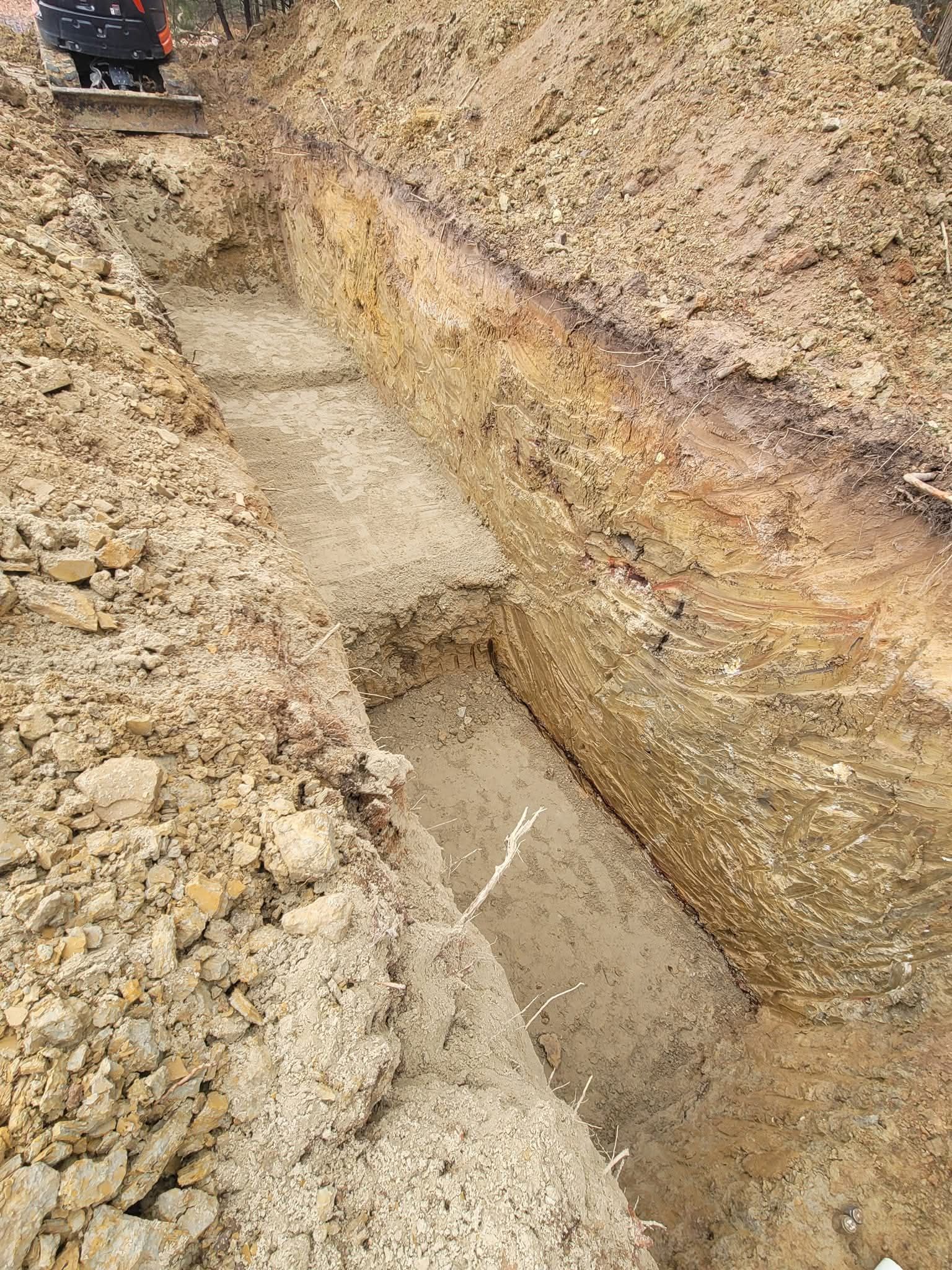 Trench dug into the earth, with exposed layers of soil.