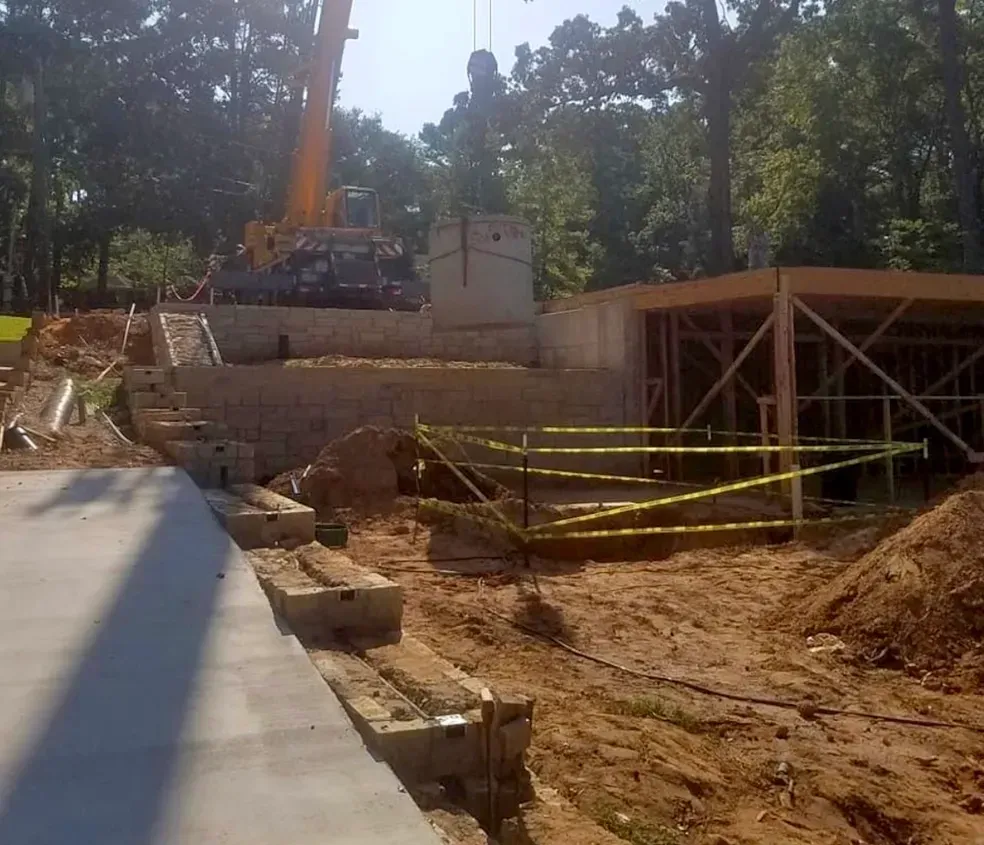 Construction site with crane, retaining wall, and building framework; sunny day.
