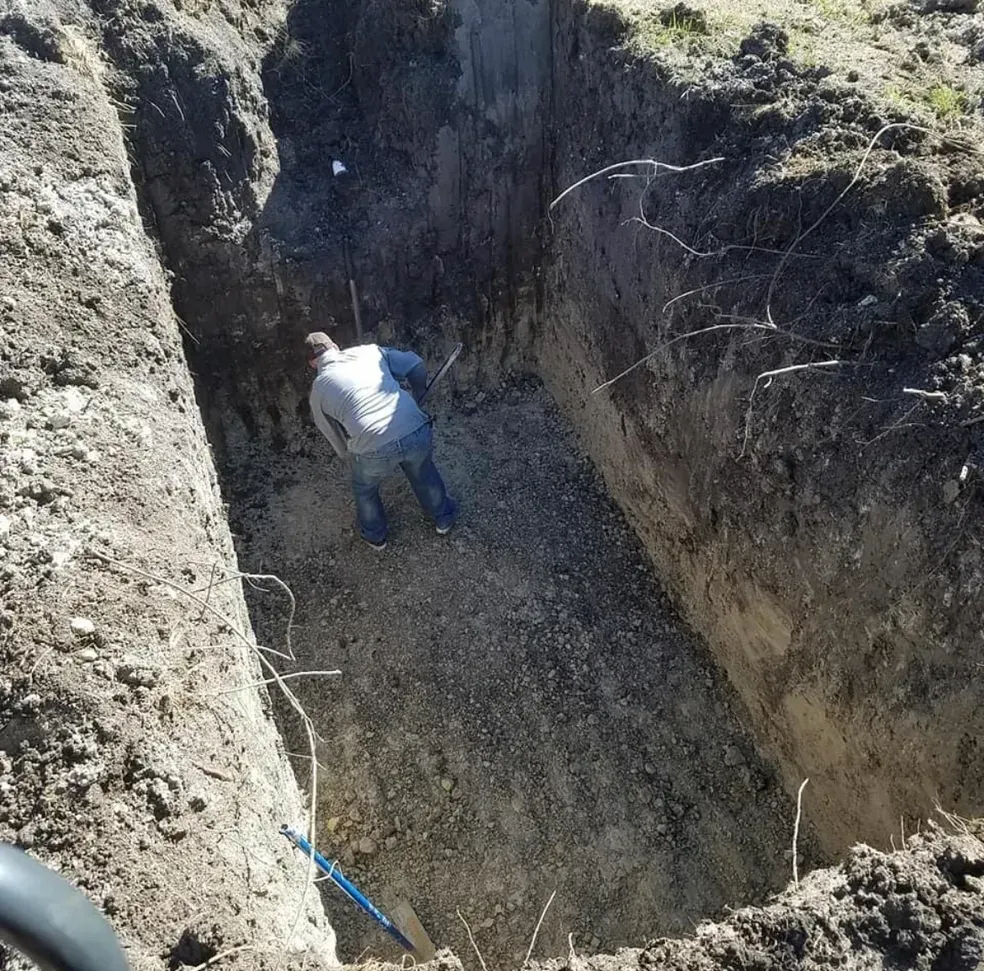 Man in a large, rectangular excavated pit, possibly constructing something.