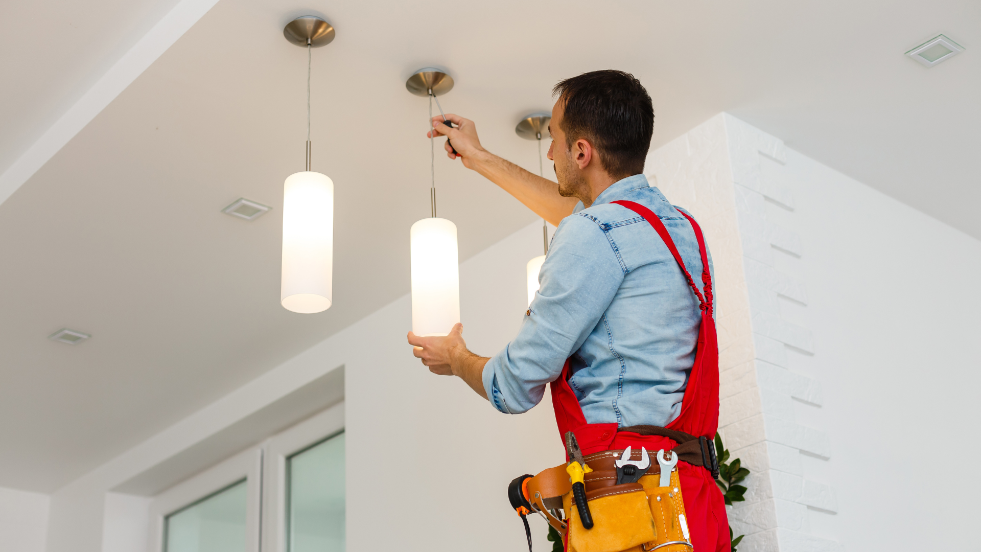A man is installing a light fixture on the ceiling.