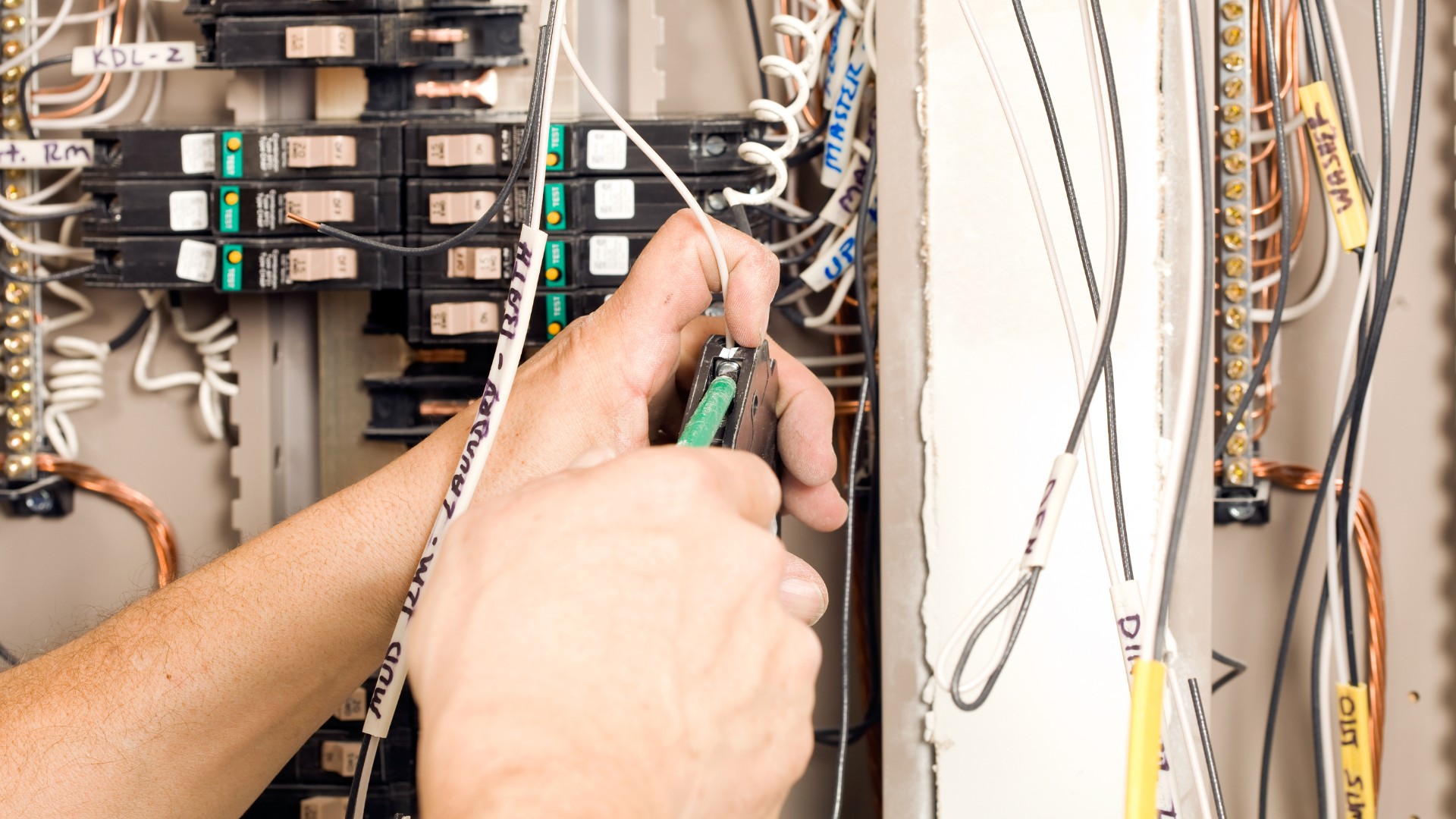 A person is working on an electrical box with a pair of pliers.