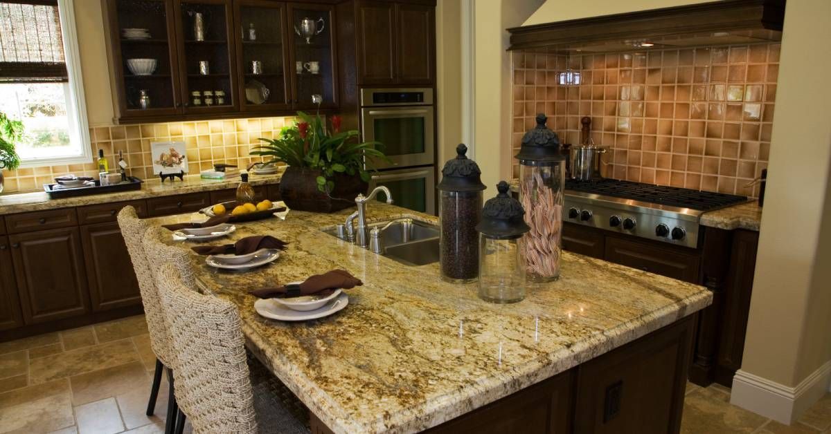 A granite countertop installed atop an island in the center of a residential kitchen. The kitchen is dimly lit.