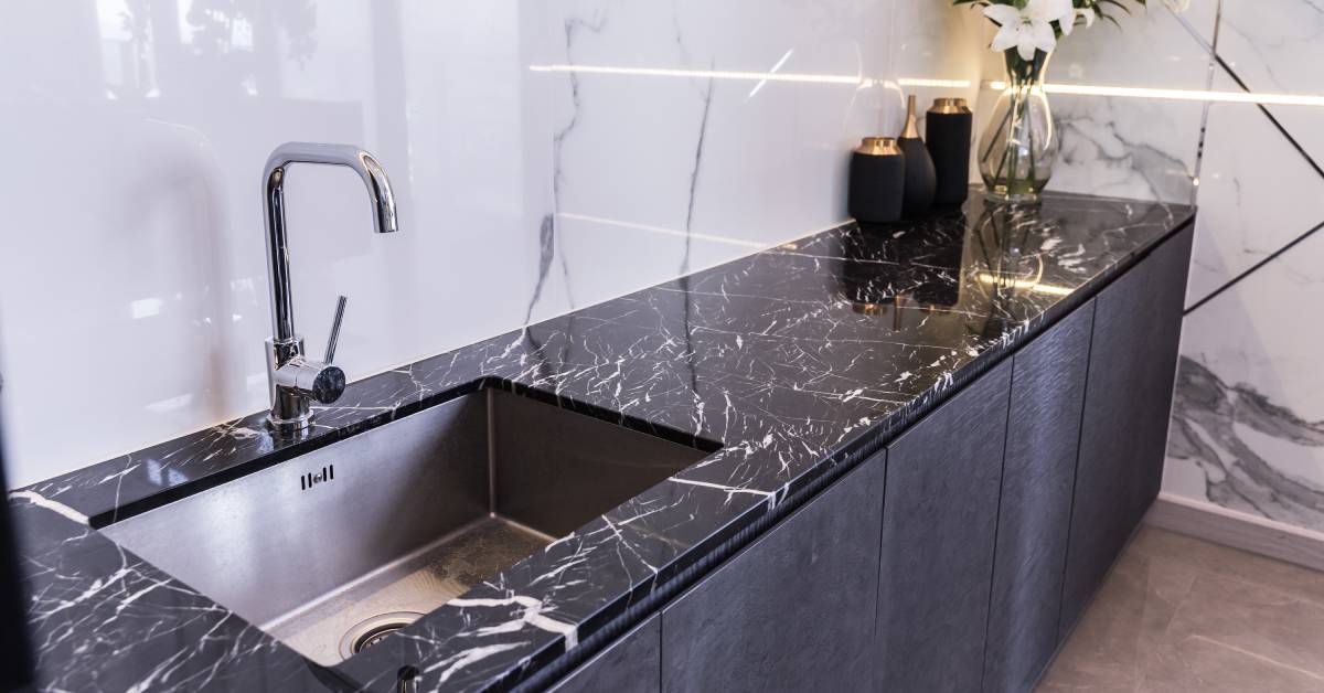 A granite countertop with a sink on it is installed against the wall in a kitchen. The sink is empty.