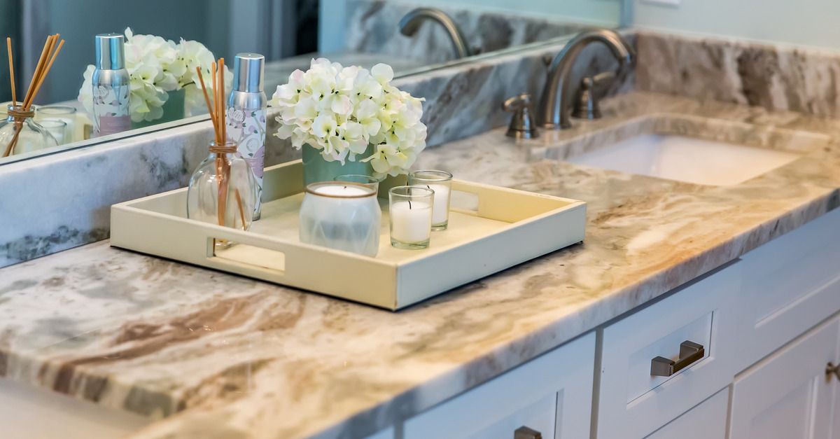 A bathroom with a large granite countertop. A tray on the countertop holds decorative materials, including candles.