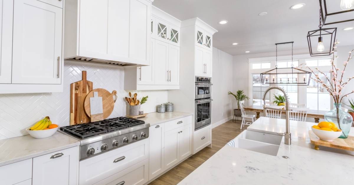 A large clean residential kitchen during the day. All the cabinets and countertops in the kitchen are white.