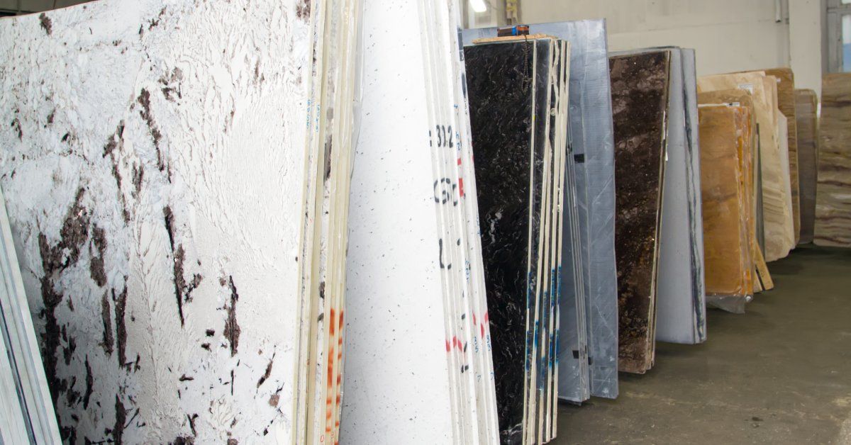 A wide collection of massive stone slabs in different colors being stored together in a large warehouse.