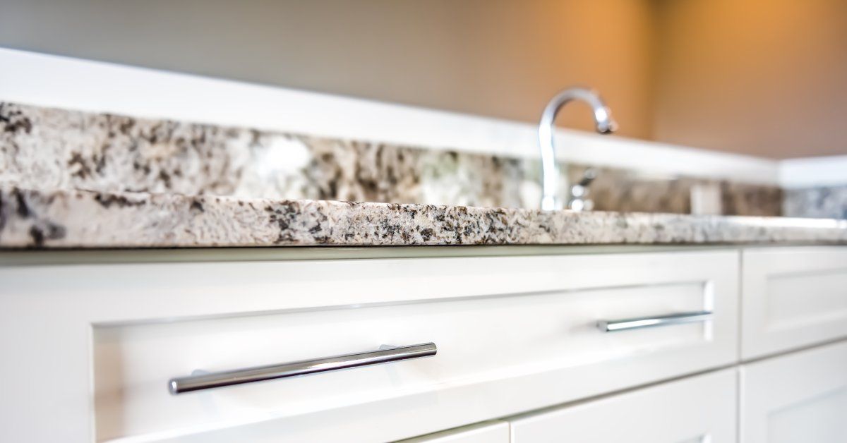 A granite countertop in a residential kitchen. The counter is attached to white wooden drawers with metal handles.