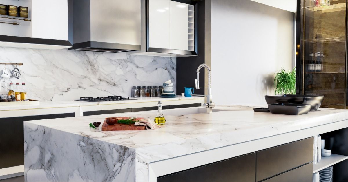 A residential kitchen with an island in the center. The island has a quartz countertop and a waterfall edge design.