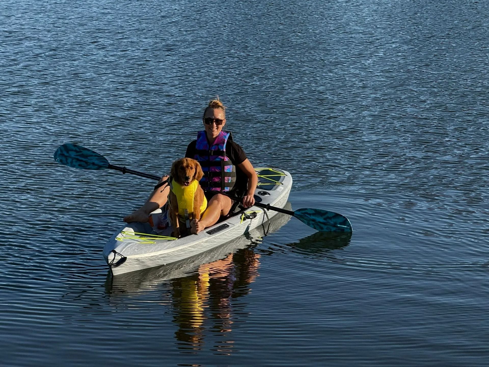 Two people in a kayak on calm water, paddling near the surface reflections.