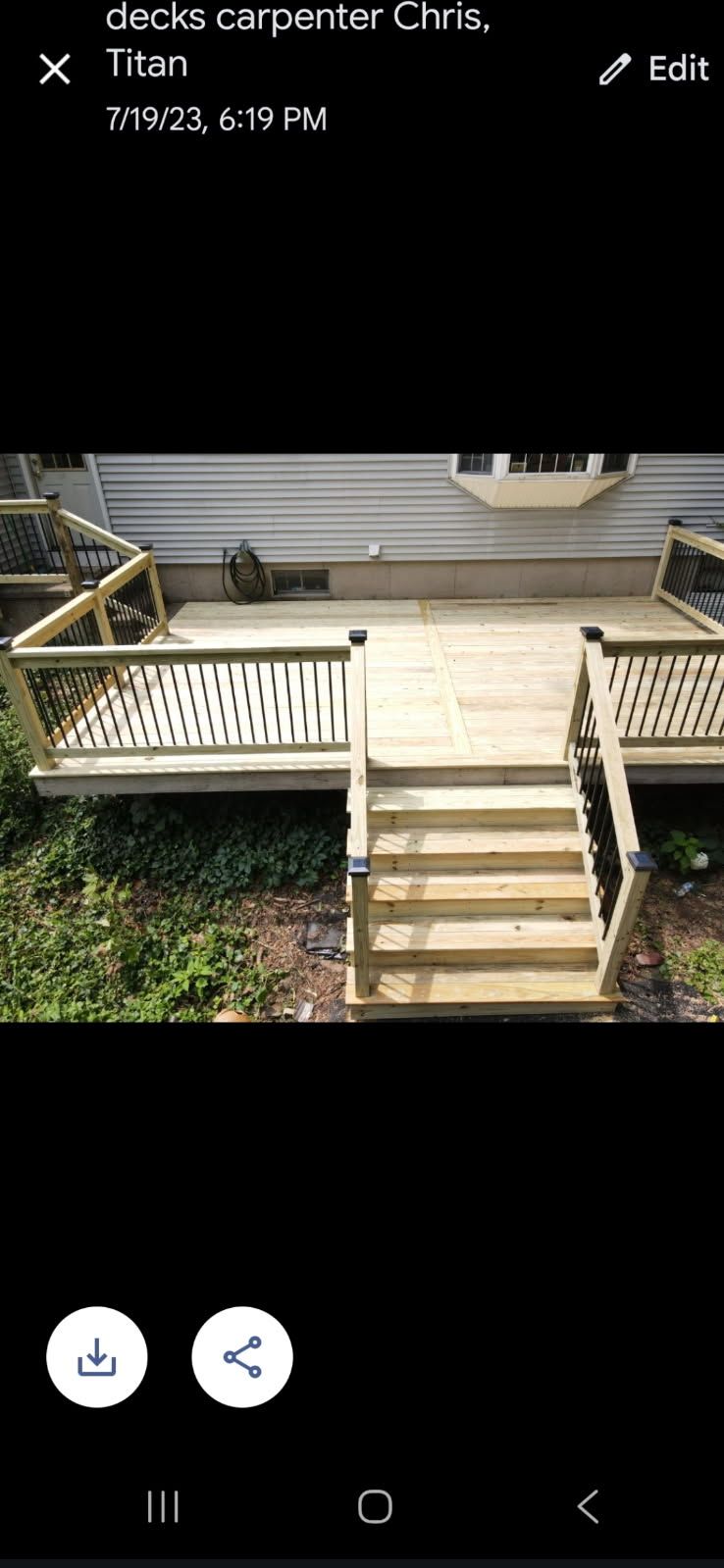 Wooden deck boards laid on joists at an outdoor construction site, with a worker in the background